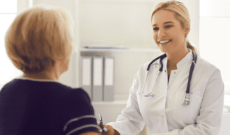 A young, white female doctor speaks to an elderly woman