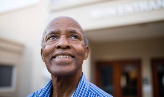 a elderly man smiles while looking up at the sky