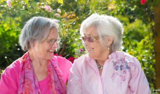 2 elderly women in assisted living share a smile together