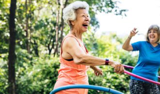 a elderly woman hulahoops outside with a large smile, Assisted Living at Paradise Village in Southern California