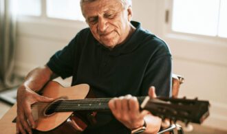 an elderly man plays guitar for mental wellness