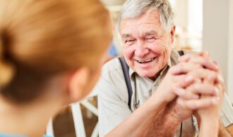 a elderly man holds the hands of a caretaker with a big smile, Memory Care at Montage Creek
