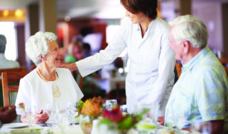 A woman at a restaurant checks in at a table where an elderly couple sits