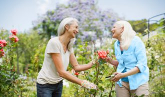 A woman smiles as she hands another woman a pink flower, Paradise Village in National City California