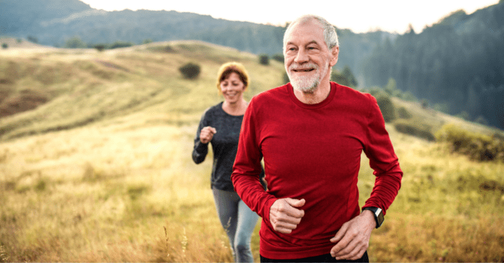 A senior living couple jog in front of a scenic hillscape