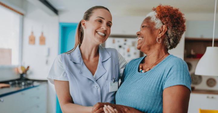 An elderly woman smiles at her assisted living assistant