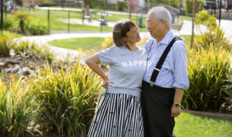 A couple stands in the gardens at Paradise Village Assisted Living in Southern California